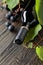 Unopened red wine bottle, vine twig, and ripe grapes on an old wooden table