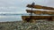 Unpainted wooden bench on a pebble beach.