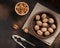 Unpeeled walnuts, nutcracker and peeled kernels on a brown background.