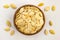 Unpeeled white color pumpkin seeds poured from bamboo bowl on white background