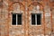 Unplastered brick wall of a building with two windows