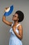 Unpleased black woman suffer from heat inside, overheated african female waving with paper fan