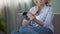 Unpleased retired woman sitting on couch and looking into a hand mirror, age