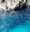 unreal blue sea water with tints of color hides in a dark mysterious grotto in a white relief rock