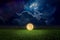 Unreal fantastic image - luminous sphere, similar to full moon, levitates over green field. Bright stars, glowing nebula and