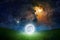 Unreal fantastic image - luminous sphere, similar to full moon, levitates over green grass. Bright stars, glowing nebula in dark