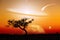 Unreal landscape of lone tree silhouette with planet and galaxy