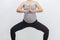 Unrecognisable pregnant woman practicing yoga in horse pose ackground with copy space