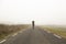 Unrecognisable woman, walking on a cold and foggy mountain road