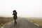 Unrecognisable woman, walking on a cold and foggy mountain road