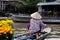 Unrecognisable Woman wearing traditional Vietnamese hat, rowing on a boat full of flowers to prepare Tet, Mekong Delta, Vietnam
