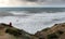 Unrecognised person standing the edge of a cliff end enjoying the dramatic stormy sea and sky