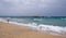 Unrecognised person walking in a tropical sandy beach. Outdoor activity. Windy stormy waves.