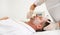 Unrecognizable aesthetician applying beauty cosmetic product with a brush on the face of a handsome mature man lying down on a
