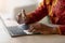 Unrecognizable african man sanitizing laptop keyboard surface with disinfectant spray, closeup