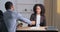 Unrecognizable afro american business man sitting at office table gives money salary dollars to confident curly woman