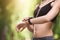 Unrecognizable athlete woman checking fitness bracelet indicators while jogging outdoors, closeup