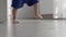 unrecognizable baby toddler doing first steps barefoot, grey floor room indoors