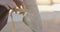 Unrecognizable ballerina tying laces on pointe shoes in slowmo. Close-up of female Caucasian foot on tiptoe with sunrise