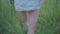 Unrecognizable barefoot Caucasian woman walking on green summer grass and closing camera with retro dress. Feet of young