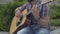 Unrecognizable bearded male musician performing on summer day. Young Caucasian man playing guitar in urban city