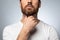 Unrecognizable bearded man touching painful neck, suffering from sore throat for flu, cold or infection, grey background