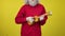 Unrecognizable bearded senior man playing ukulele on yellow background and singing. Male Caucasian musician performing