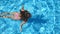 Unrecognizable beautiful girl floating across the pool of hotel. Young woman swimming in clear blue water of basin on