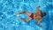 Unrecognizable beautiful girl in red bikini floating across the pool of hotel. Young woman swimming in clear blue water