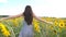 Unrecognizable beautiful girl running on yellow sunflower field. Happy young woman jogging through the meadow during