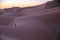 Unrecognizable Berber man walking on a dreamy desert at Twilight of dawn. Desert dune of Erg Chigaga, at the gates of the Sahara.