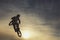 Unrecognizable biker performing acrobatic jump at sunny sky - Guy riding bmx bicycle at extreme sport competition on