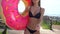 Unrecognizable Bikini girl walking with sprinkled donut float at pool in sun day. Party, hotel, beach, holiday, vacation