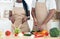 Unrecognizable black couple in aprons preparing healthy vegetable salad together in kitchen