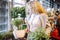 Unrecognizable blonde with curly hair chooses plants for winter garden in garden center. Unpretentious plants. Hobby.