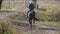 Unrecognizable blonde woman riding on purebred black horse at sunny day. Female jockey horseback walking along meadow