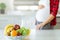 unrecognizable blurred pregnant woman on kitchen in red shirt  hold hand on belly on front table bowl with mix fruits  healthy