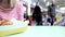 Unrecognizable blurred woman sitting with her son by the table in the mall food court and they are eating nuggets from a box