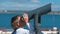 Unrecognizable boy looks through binoculars at the sea.