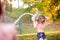 Unrecognizable boy splashing girl with water gun, sunny summer