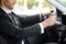 Unrecognizable businessman holding hands on steering wheel, driving car