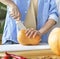 Unrecognizable caucasian man chopping pumpkin on a board