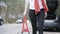 Unrecognizable Caucasian woman installing red triangle sign on suburban road. Misfortune on countryside road, female