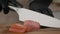 Unrecognizable Chef Cutting Fresh Salmon Wearing Gloves In Kitchen, Closeup