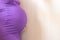 Unrecognizable Close up Pregnant women. Hands over tummy during last month of pregnancy. In violet color dress on light