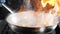 Unrecognizable cook tossing hot non-stick frying pan with seafood , then setting it on fire cooking flambe dish. Slow