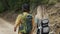 Unrecognizable couple backpackers walking by forest's rocky path