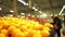 Unrecognizable customers in supermarket choose oranges