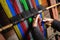 Unrecognizable elder woman\'s hands using a homemade craft loom to weave colorful wool