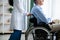 Unrecognizable elderly male patient in wheelchair and his female caregiver at retirement home, cropped view